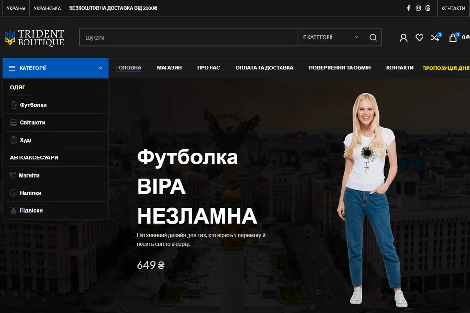 Trident Boutique: the “Faith Unbreakable” T-shirt on a model against Kyiv at dusk, with the clothing categories on the left